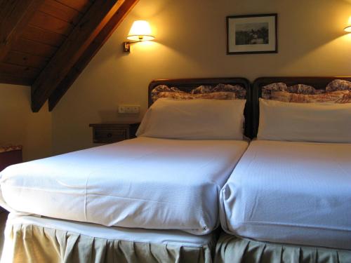 two beds in a bedroom with white sheets at Besiberri in Arties