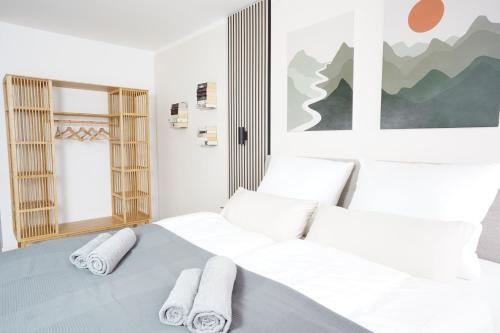 a white bedroom with two beds with towels at Kur-Apartment Matilda in Waldbronn