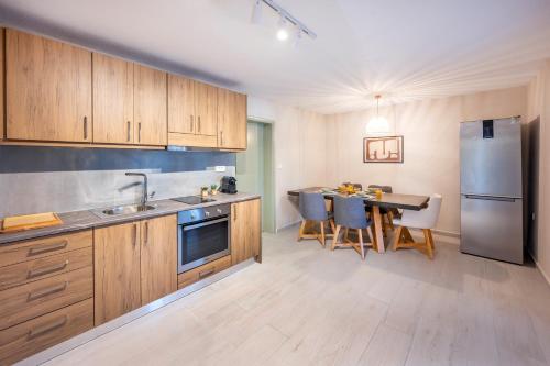 a kitchen with wooden cabinets and a table and a refrigerator at Kos Infinity Suites in Kos Town