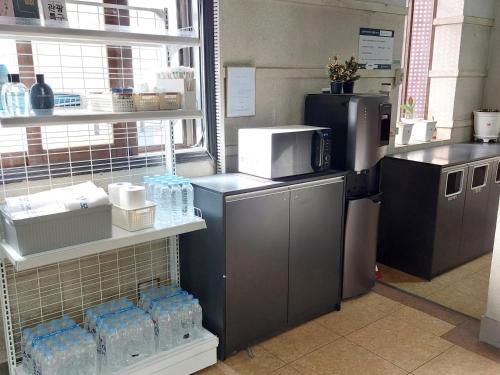 a kitchen with bottles of water and a refrigerator at Mokhwajang Motel in Goyang