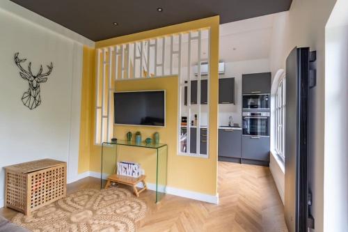 Il comprend un salon avec des murs jaunes et une cuisine. dans l'établissement Le Lodge des Villettes, à Jouy-le-Moutier