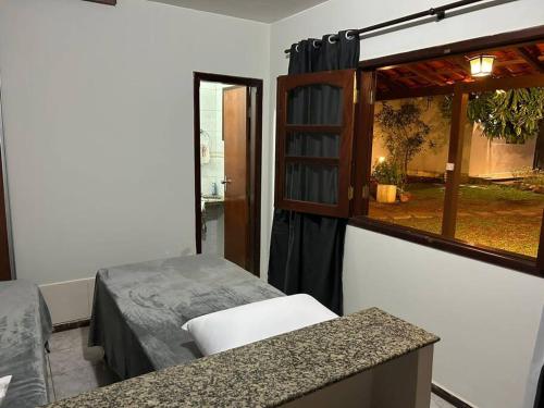 Habitación pequeña con cama y ventana en Suíte c/ar e varanda perto do Parque de Exposições, en Patos de Minas