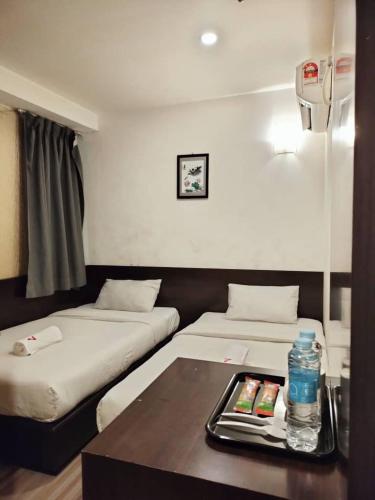 a room with two beds and a table with a tray at 7 Hotel in Juru
