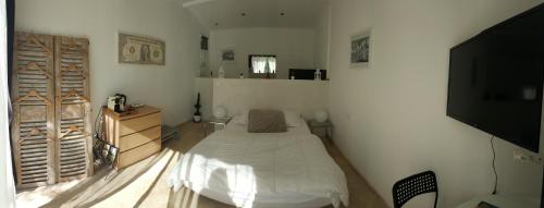 une chambre avec un lit et une télévision à écran plat dans l'établissement Chambre blanche, à Saint-Quentin-la-Poterie