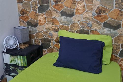 a green and blue pillow on a bed with a stone wall at In The Heart Of Praia - Family B&B in Praia