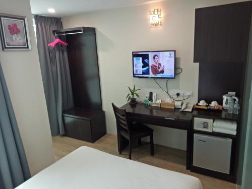 een hotelkamer met een bureau en een tv aan de muur bij 7 Hotel in Juru