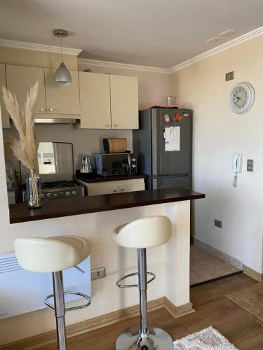 a kitchen with two bar stools and a black refrigerator at Departamento nuevo y acogedor in Villarrica