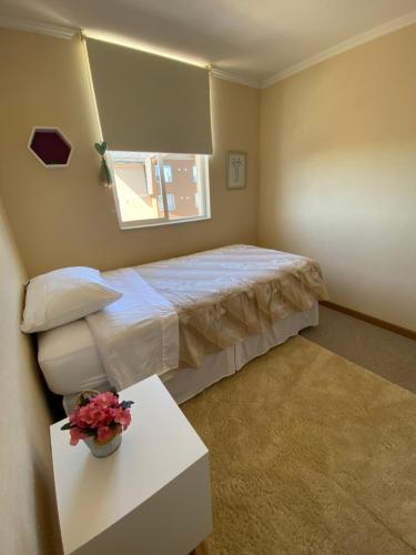 a bedroom with a bed and a table and a window at Departamento nuevo y acogedor in Villarrica