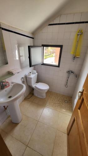 a bathroom with a toilet and a sink and a window at VILLA COQUETTE in Ngaparou