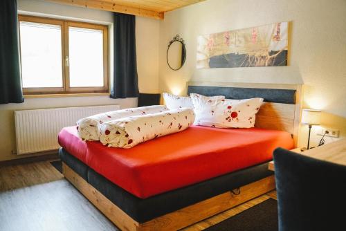 Schlafzimmer mit einem Bett mit roter Bettwäsche und Kissen in der Unterkunft Birkenheim in Sankt Leonhard im Pitztal