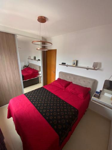 a bedroom with a red bed with a red blanket at Apartamento Vila Tupi in Praia Grande