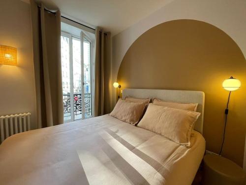 une chambre avec un grand lit avec une grande fenêtre dans l'établissement Marais - Bright one-bedroom decorated with taste, à Paris