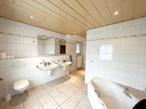 a bathroom with a tub and two sinks and a toilet at Cozy Workers Apartment in Siegburg in Siegburg