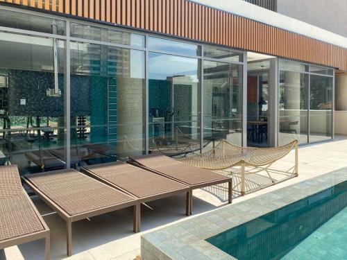 een gebouw met een zwembad en een patio met tafels en stoelen bij Apt. inteiro recém-reformado - Vila Mariana in Sao Paulo