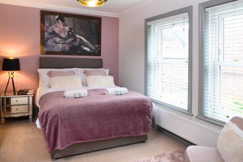 a bedroom with a bed with purple sheets and windows at The Old Brewery Boardroom - Winchester City Centre, Free Parking for 2 Cars, Sleeps 6 in Winchester