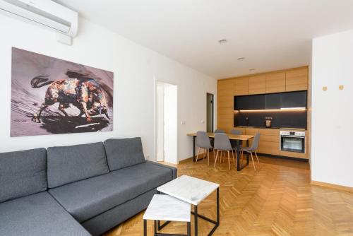 ein Wohnzimmer mit einem grauen Sofa und einer Küche in der Unterkunft Tim 3 in Belgrad