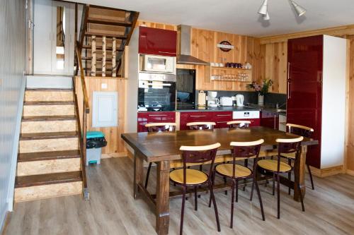 une cuisine avec une table en bois et quelques chaises dans l'établissement Les Genêts du Sancy, à Besse-et-Saint-Anastaise