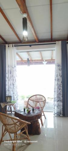 een kamer met een tafel en stoelen en een groot raam bij Black Bridge View Cottage in Ella