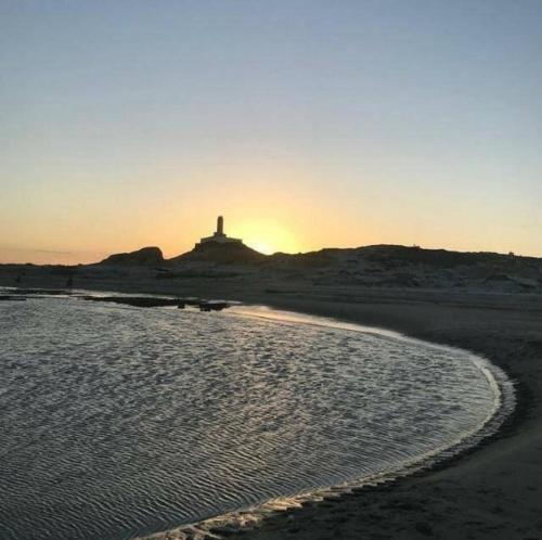 a beach with the sun setting in the background at Bangalô pontal beach house in Fortim