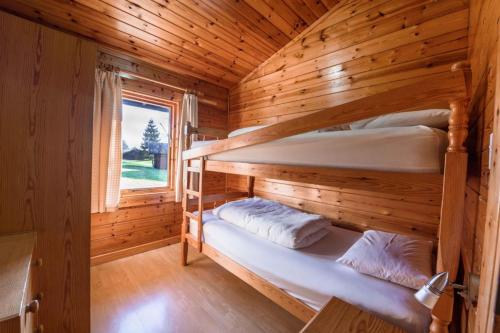 two bunk beds in a wooden cabin with a window at Pinecroft Lodges in Ingleton 