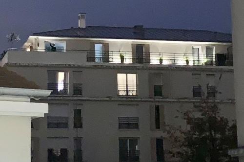 - un grand bâtiment blanc avec un homme sur le balcon dans l'établissement Apt w/ view on the Eiffel Tower, à Soisy-sous-Montmorency