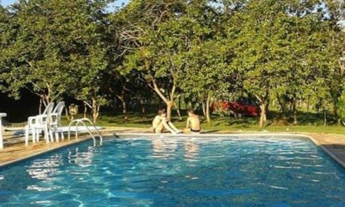 two people sitting next to a swimming pool at HOTEL FAZENDA CANARIO DA TERRA in Rio Novo