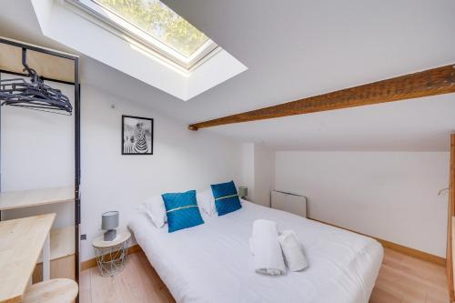 une chambre avec un lit blanc avec des oreillers bleus dans l'établissement Le Lafontaine - T3 Quartier Victoire, à Bordeaux