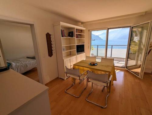 een eetkamer met een tafel en stoelen en uitzicht op de oceaan bij Lake Lucerne Paradise apartment in Brunnen