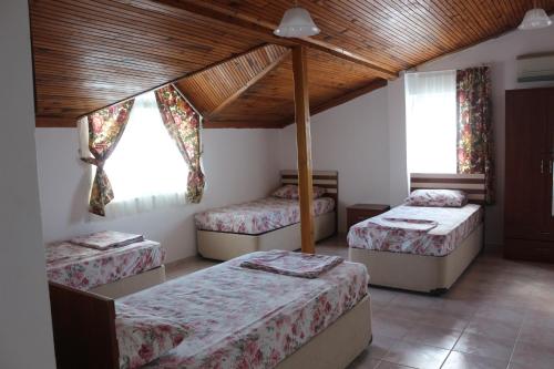 Habitación con 3 camas y techo de madera. en Trekios Pansiyon & Cafe, en Eceabat