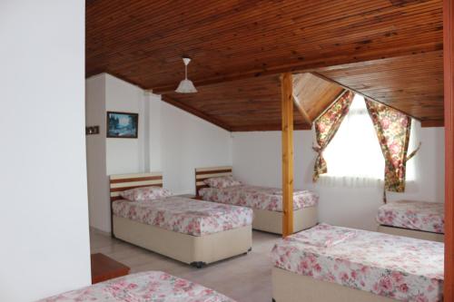 a bedroom with three beds and a wooden ceiling at Trekios Pansiyon & Cafe in Eceabat