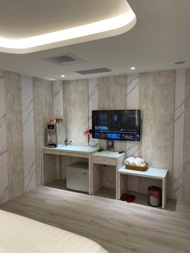 a room with a desk with a television and a bed at Benz Hotel in Zhongli