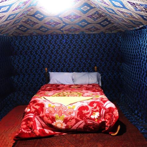 una cama en una habitación con una pared azul en Bivouac la fibule des Dunes, en Merzouga