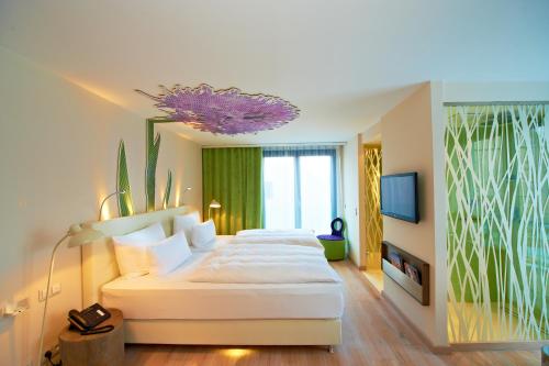 a hotel room with a large white bed and a tv at Hotel-Restaurant Schwanen in Metzingen