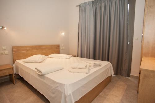 a bedroom with a bed with white sheets and towels at Villa Gerasmia in Trapezaki