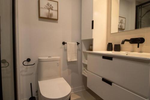 a white bathroom with a toilet and a sink at Downtown Montreal Premium Cozy Studio in Montréal