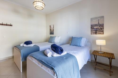 een slaapkamer met twee bedden met blauwe lakens en een tafel bij Sun Lovers Home by Seewest in Lagos