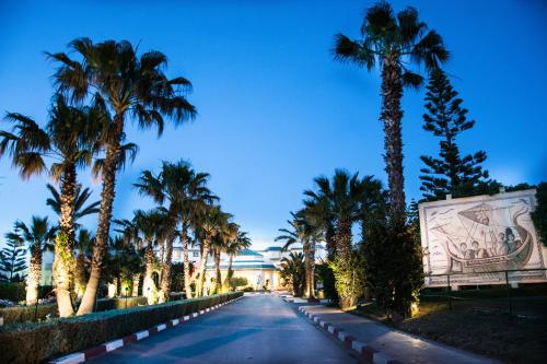 a street lined with palm trees and a building at Sentido Bellevue Park in Port El Kantaoui