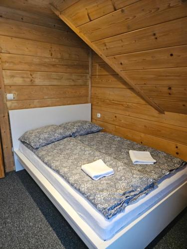 a bed in a room with wooden walls at Domek Góralski Amelka in Poronin