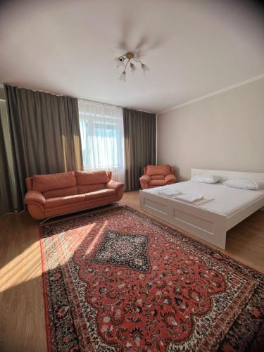 1 dormitorio con cama, sofá y alfombra en 452 Возле Байтерека для компании 1-6 человек с 2 кроватями и диваном en Astaná