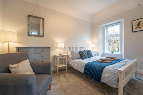 a bedroom with a bed and a chair and a mirror at Argaty Cottage in Doune