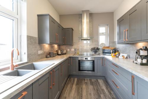 a kitchen with blue cabinets and a sink at Argaty Cottage in Doune
