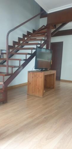 uma televisão numa mesa de madeira num quarto com uma escada em Casa Telares Ávila em Ávila