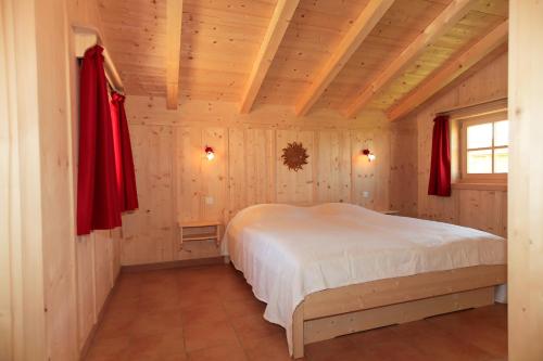 ein Schlafzimmer mit einem Bett in einem Zimmer mit Holzwänden in der Unterkunft Alpenchalets Hotel Lambach in Seebruck