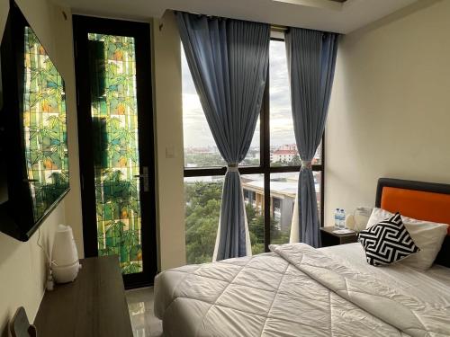 a bedroom with a bed and large windows at Okide F0525 in Phnom Penh