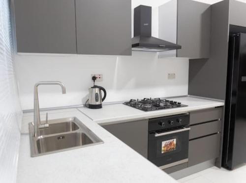 a white kitchen with a sink and a stove at Greenfield’s Apartment in Amrahia