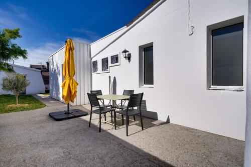 een patio met een tafel en stoelen en een parasol bij Lovely house Bordeaux Cenon with garden in Cenon