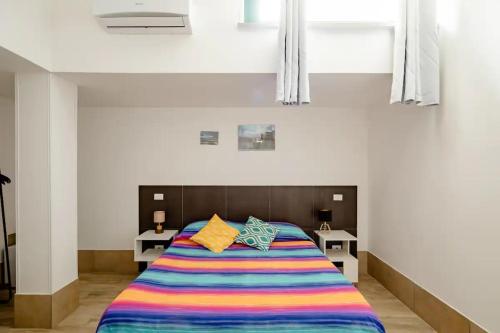 a bedroom with a bed with a colorful striped blanket at L'ANFORA DELLE MURELLE in Torre di Montalto