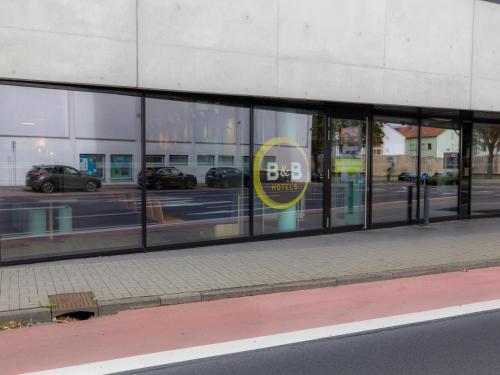 une fenêtre avant de magasin d'un bâtiment avec des voitures dans l'établissement B&B Hotel Fulda-City, à Fulde