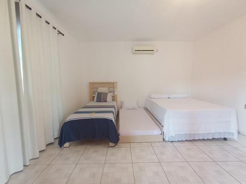 two beds in a room with white walls and tile floors at Casa Bela vista São José in Piranhas