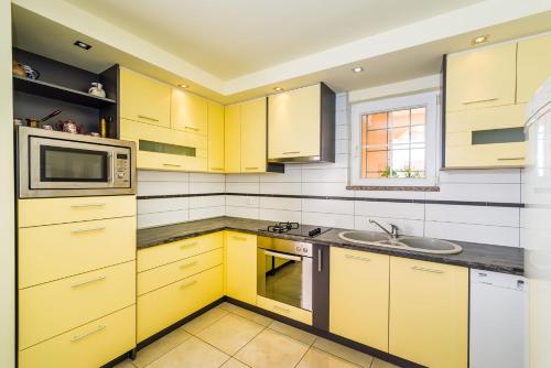 a yellow kitchen with a sink and a microwave at Villa Dalmatina Zadar mit Pool in Zadar
